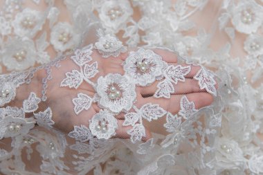 Doku danteli kumaş. Beyaz arka plan stüdyosunda dantel. İplik ya da iplikten yapılmış ince kumaş. Fildişi renkli dantel kumaşın arkaplan resmi. Bej arkaplanda beyaz dantel.