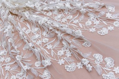 Doku danteli kumaş. Beyaz arka plan stüdyosunda dantel. İplik ya da iplikten yapılmış ince kumaş. Fildişi renkli dantel kumaşın arkaplan resmi. Bej arkaplanda beyaz dantel.