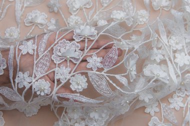 Doku danteli kumaş. Beyaz arka plan stüdyosunda dantel. İplik ya da iplikten yapılmış ince kumaş. Fildişi renkli dantel kumaşın arkaplan resmi. Bej arkaplanda beyaz dantel.