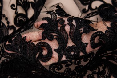 Doku danteli kumaş. Beyaz arka plan stüdyosunda dantel. İplik ya da iplikten yapılmış ince kumaş. Fildişi renkli dantel kumaşın arkaplan resmi. Bej arkaplanda siyah dantel.