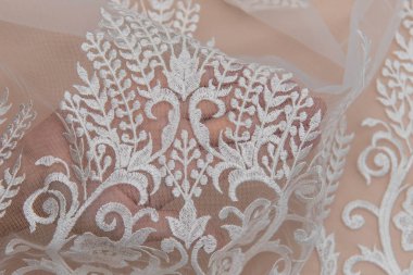 Doku danteli kumaş. Beyaz arka plan stüdyosunda dantel. İplik ya da iplikten yapılmış ince kumaş. Fildişi renkli dantel kumaşın arkaplan resmi. Bej arkaplanda beyaz dantel.