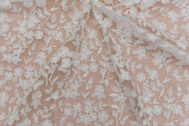 Doku danteli kumaş. Beyaz arka plan stüdyosunda dantel. İplik ya da iplikten yapılmış ince kumaş. Fildişi renkli dantel kumaşın arkaplan resmi. Bej arkaplanda beyaz dantel.