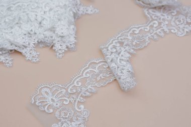 Doku danteli kumaş. Beyaz arka plan stüdyosunda dantel. İplik ya da iplikten yapılmış ince kumaş. Fildişi renkli dantel kumaşın arkaplan resmi. Bej arkaplanda beyaz dantel.