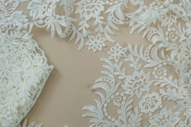 Doku danteli kumaş. Beyaz arka plan stüdyosunda dantel. İplik ya da iplikten yapılmış ince kumaş. Fildişi renkli dantel kumaşın arkaplan resmi. Bej arkaplanda beyaz dantel.
