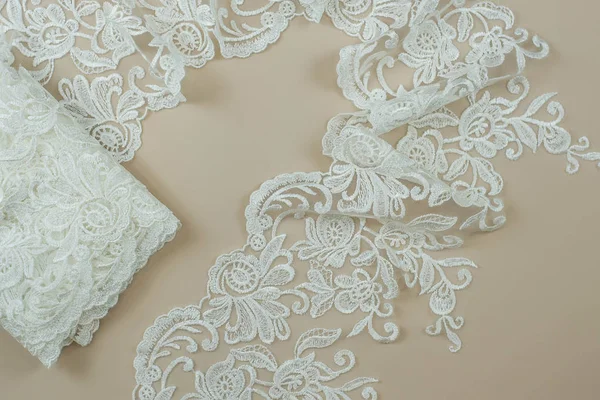 Texture lace fabric. lace on white background studio. thin fabric made of yarn or thread. a background image of ivory-colored lace cloth. White lace on beige background.