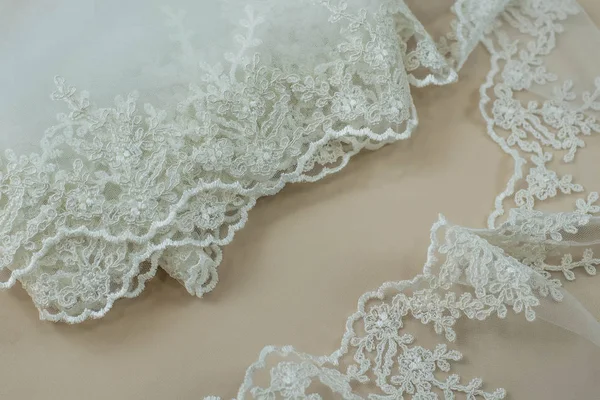 Texture lace fabric. lace on white background studio. thin fabric made of yarn or thread. a background image of ivory-colored lace cloth. White lace on beige background.