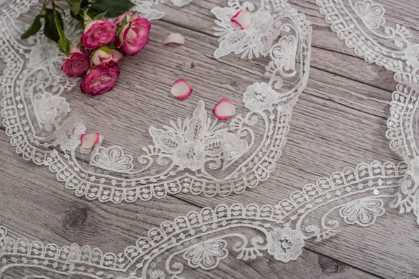 Fondo bianco in legno con fiori bianchi primaverili rose e nastro di pizzo. Felice giorno delle donne. La trama del pizzo su sfondo di legno. — Foto Stock