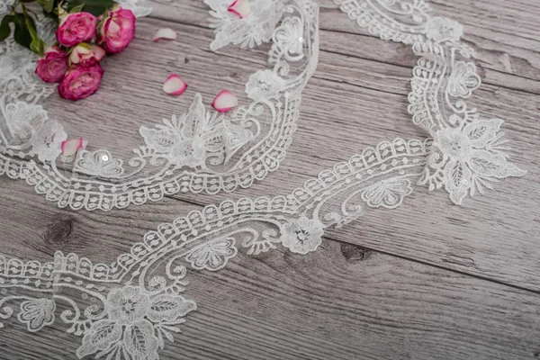 White wooden background with white spring flowers roses and lace ribbon. Happy womans day. The texture of lace on wooden background. — Stock Photo, Image