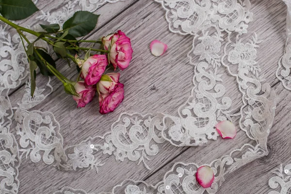 Fondo bianco in legno con fiori bianchi primaverili rose e nastro di pizzo. Felice giorno delle donne. La trama del pizzo su sfondo di legno. — Foto Stock