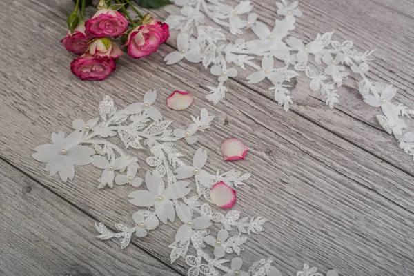 Bílé dřevěné pozadí s bílými jarními květy růží a krajkové stuhy. Šťastný den žen. Textura krajky na dřevěném pozadí. — Stock fotografie