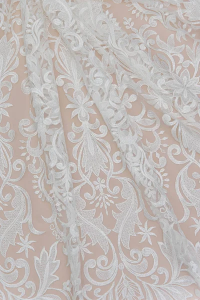 A background image of ivory-colored lace cloth. White lace on beige background. — Stock Photo, Image