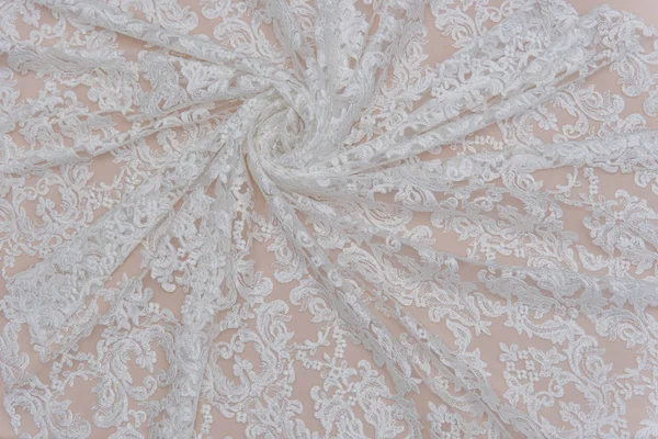 a background image of ivory-colored lace cloth. White lace on beige background.