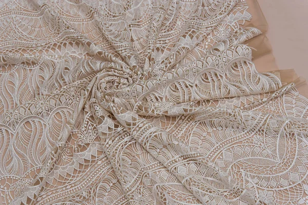 A background image of ivory-colored lace cloth. White lace on beige background. — Stock Photo, Image