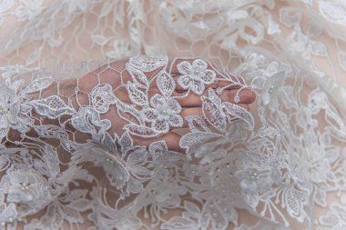 Doku danteli kumaş. Beyaz arka plan stüdyosunda dantel. İplik ya da iplikten yapılmış ince kumaş. Fildişi renkli dantel kumaşın arkaplan resmi. Bej arkaplanda beyaz dantel.