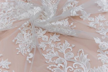 Doku danteli kumaş. Beyaz arka plan stüdyosunda dantel. İplik ya da iplikten yapılmış ince kumaş. Fildişi renkli dantel kumaşın arkaplan resmi. Bej arkaplanda beyaz dantel.