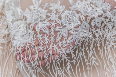 Doku danteli kumaş. Beyaz arka plan stüdyosunda dantel. İplik ya da iplikten yapılmış ince kumaş. Fildişi renkli dantel kumaşın arkaplan resmi. Bej arkaplanda beyaz dantel.