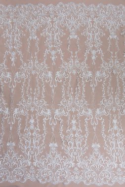 Doku danteli kumaş. Beyaz arka plan stüdyosunda dantel. İplik ya da iplikten yapılmış ince kumaş. Fildişi renkli dantel kumaşın arkaplan resmi. Bej arkaplanda beyaz dantel.