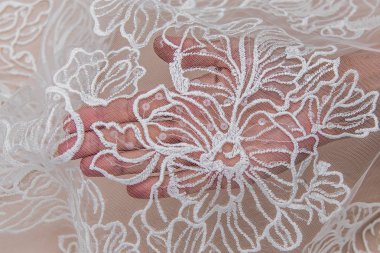 Doku danteli kumaş. Beyaz arka plan stüdyosunda dantel. İplik ya da iplikten yapılmış ince kumaş. Fildişi renkli dantel kumaşın arkaplan resmi. Bej arkaplanda beyaz dantel.