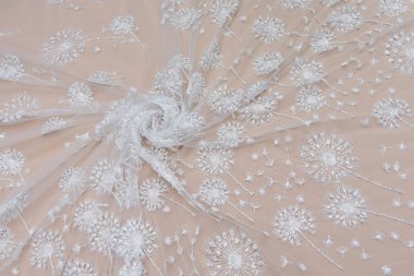 Doku danteli kumaş. Beyaz arka plan stüdyosunda dantel. İplik ya da iplikten yapılmış ince kumaş. Fildişi renkli dantel kumaşın arkaplan resmi. Bej arkaplanda beyaz dantel.