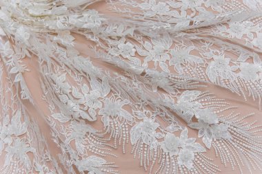 Doku danteli kumaş. Beyaz arka plan stüdyosunda dantel. İplik ya da iplikten yapılmış ince kumaş. Fildişi renkli dantel kumaşın arkaplan resmi. Bej arkaplanda beyaz dantel.