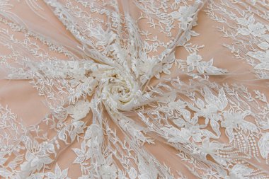 Doku danteli kumaş. Beyaz arka plan stüdyosunda dantel. İplik ya da iplikten yapılmış ince kumaş. Fildişi renkli dantel kumaşın arkaplan resmi. Bej arkaplanda beyaz dantel.