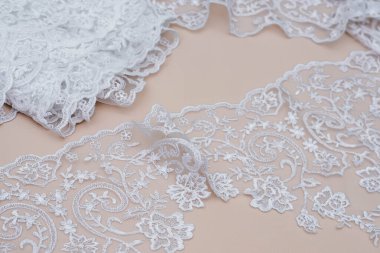 Doku danteli kumaş. Beyaz arka plan stüdyosunda dantel. İplik ya da iplikten yapılmış ince kumaş. Fildişi renkli dantel kumaşın arkaplan resmi. Bej arkaplanda beyaz dantel.