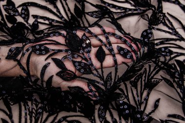 Doku danteli kumaş. Beyaz arka plan stüdyosunda dantel. İplik ya da iplikten yapılmış ince kumaş. Fildişi renkli dantel kumaşın arkaplan resmi. Bej arkaplanda siyah dantel.