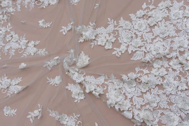 Doku danteli kumaş. Beyaz arka plan stüdyosunda dantel. İplik ya da iplikten yapılmış ince kumaş. Fildişi renkli dantel kumaşın arkaplan resmi. Bej arkaplanda beyaz dantel.