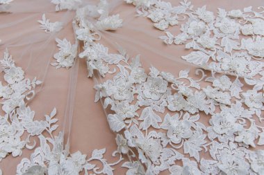 Doku danteli kumaş. Beyaz arka plan stüdyosunda dantel. İplik ya da iplikten yapılmış ince kumaş. Fildişi renkli dantel kumaşın arkaplan resmi. Bej arkaplanda beyaz dantel.