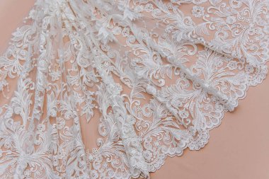 Doku danteli kumaş. Beyaz arka plan stüdyosunda dantel. İplik ya da iplikten yapılmış ince kumaş. Fildişi renkli dantel kumaşın arkaplan resmi. Bej arkaplanda beyaz dantel.