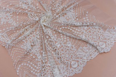 Doku danteli kumaş. Beyaz arka plan stüdyosunda dantel. İplik ya da iplikten yapılmış ince kumaş. Fildişi renkli dantel kumaşın arkaplan resmi. Bej arkaplanda beyaz dantel.
