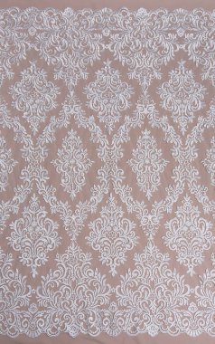 Doku danteli kumaş. Beyaz arka plan stüdyosunda dantel. İplik ya da iplikten yapılmış ince kumaş. Fildişi renkli dantel kumaşın arkaplan resmi. Bej arkaplanda beyaz dantel.