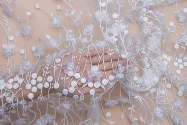 Doku danteli kumaş. Beyaz arka plan stüdyosunda dantel. İplik ya da iplikten yapılmış ince kumaş. Fildişi renkli dantel kumaşın arkaplan resmi. Bej arkaplanda beyaz dantel.