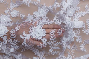 Doku danteli kumaş. Beyaz arka plan stüdyosunda dantel. İplik ya da iplikten yapılmış ince kumaş. Fildişi renkli dantel kumaşın arkaplan resmi. Bej arkaplanda beyaz dantel.