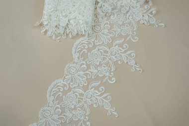 Doku danteli kumaş. Beyaz arka plan stüdyosunda dantel. İplik ya da iplikten yapılmış ince kumaş. Fildişi renkli dantel kumaşın arkaplan resmi. Bej arkaplanda beyaz dantel.