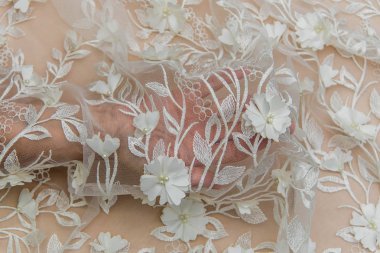 Doku danteli kumaş. Beyaz arka plan stüdyosunda dantel. İplik ya da iplikten yapılmış ince kumaş. Fildişi renkli dantel kumaşın arkaplan resmi. Bej arkaplanda beyaz dantel.