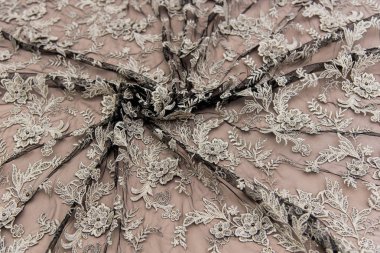 Doku danteli kumaş. Beyaz arka plan stüdyosunda dantel. İplik ya da iplikten yapılmış ince kumaş. Fildişi renkli dantel kumaşın arkaplan resmi. Bej arkaplanda siyah dantel.