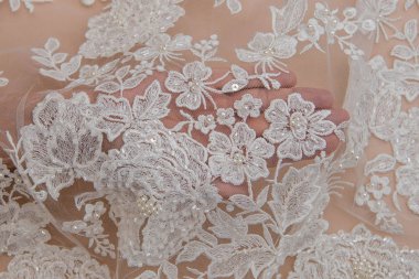 Doku danteli kumaş. Beyaz arka plan stüdyosunda dantel. İplik ya da iplikten yapılmış ince kumaş. Fildişi renkli dantel kumaşın arkaplan resmi. Bej arkaplanda beyaz dantel.