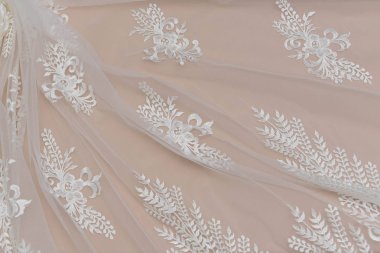 Doku danteli kumaş. Beyaz arka plan stüdyosunda dantel. İplik ya da iplikten yapılmış ince kumaş. Fildişi renkli dantel kumaşın arkaplan resmi. Bej arkaplanda beyaz dantel.