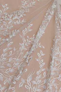 Doku danteli kumaş. Beyaz arka plan stüdyosunda dantel. İplik ya da iplikten yapılmış ince kumaş. Fildişi renkli dantel kumaşın arkaplan resmi. Bej arkaplanda beyaz dantel.