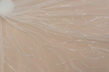 Doku danteli kumaş. Beyaz arka plan stüdyosunda dantel. İplik ya da iplikten yapılmış ince kumaş. Fildişi renkli dantel kumaşın arkaplan resmi. Bej arkaplanda beyaz dantel.