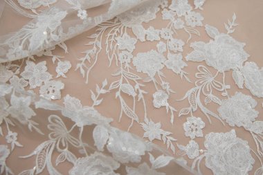 Doku danteli kumaş. Beyaz arka plan stüdyosunda dantel. İplik ya da iplikten yapılmış ince kumaş. Fildişi renkli dantel kumaşın arkaplan resmi. Bej arkaplanda beyaz dantel.