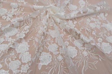 Doku danteli kumaş. Beyaz arka plan stüdyosunda dantel. İplik ya da iplikten yapılmış ince kumaş. Fildişi renkli dantel kumaşın arkaplan resmi. Bej arkaplanda beyaz dantel.