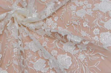 Doku danteli kumaş. Beyaz arka plan stüdyosunda dantel. İplik ya da iplikten yapılmış ince kumaş. Fildişi renkli dantel kumaşın arkaplan resmi. Bej arkaplanda beyaz dantel.