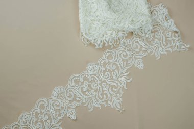 Doku danteli kumaş. Beyaz arka plan stüdyosunda dantel. İplik ya da iplikten yapılmış ince kumaş. Fildişi renkli dantel kumaşın arkaplan resmi. Bej arkaplanda beyaz dantel.