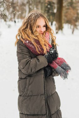 Noel, yeni yıl, kış tatili konsepti. Kıvırcık saçlı tatlı bir genç kız. Parkta karla oynamak.