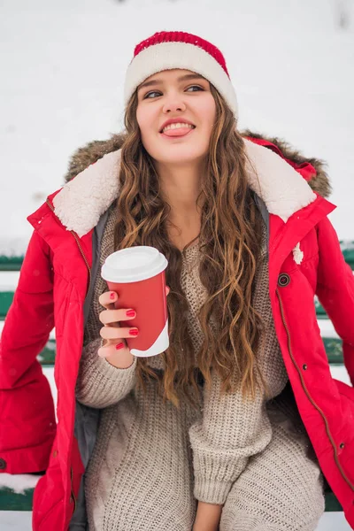 Belle adolescente mignonne souriante avec maquillage naturel et cheveux longs tient une tasse avec du café chaud ou du thé. Saison d'hiver . — Photo