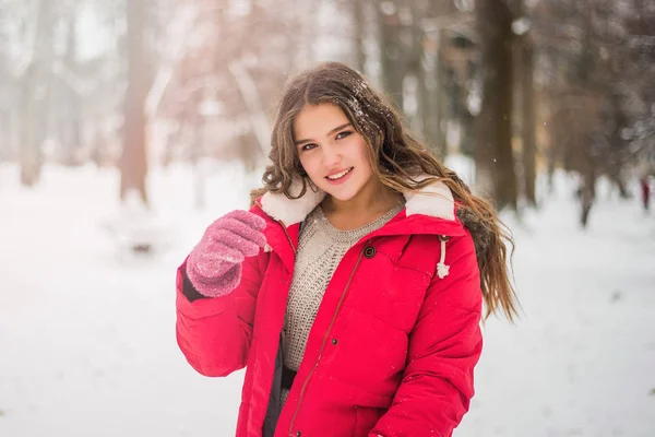Noël, Nouvel An, vacances d'hiver concept. Adolescente mignonne aux cheveux bouclés. jouer avec la neige dans le parc. — Photo