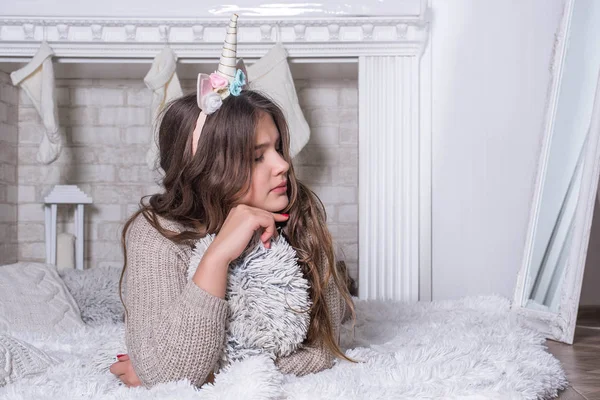 Feliz adolescente sentada cerca del árbol de Navidad. Jovencita feliz con regalos de pelo rizado junto a la chimenea cerca del árbol de Navidad. Concepto de año nuevo. Navidad.. — Foto de Stock