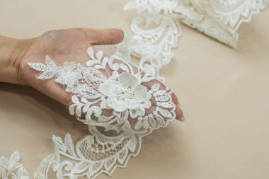 Doku danteli kumaş. Beyaz arka plan stüdyosunda dantel. İplik ya da iplikten yapılmış ince kumaş. Fildişi renkli dantel kumaşın arkaplan resmi. Bej arkaplanda beyaz dantel.